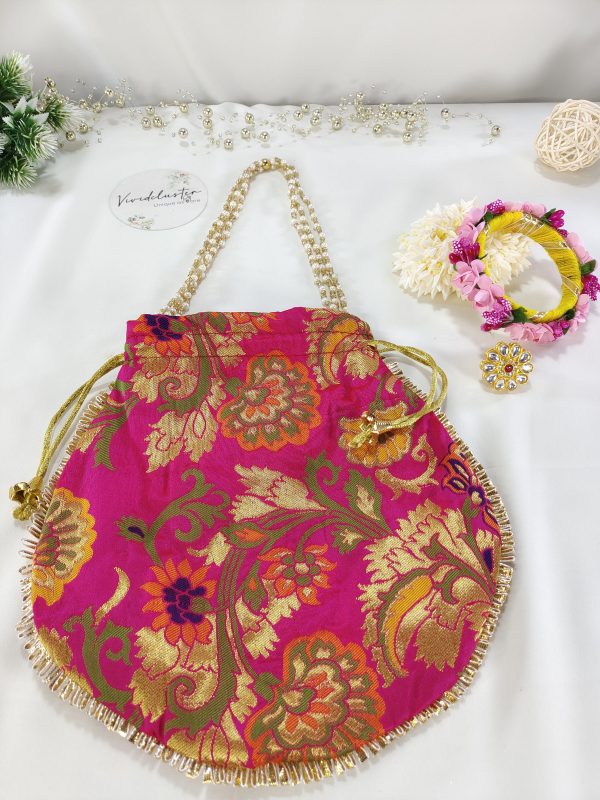 A beautifully handcrafted pink potli bag featuring detailed gold embroidery and a matching gold drawstring, ideal for use as a bridal accessory, wedding favor, or engagement ceremony pouch