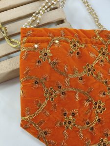 handmade potli bag is adorned with intricate golden embroidery, featuring elegant floral patterns. The orange fabric adds a vibrant touch, making it a perfect accessory for weddings, nikah ceremonies, and bridal showers.