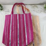 a set of vibrant potli bags, perfect for wedding gifts and bridal shower favors. The bags, adorned with silver stripes, come in a deep pink and a soft peach hue