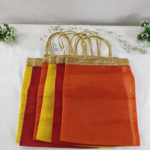 collection of bridal silk potli bags featuring rich hues of orange, red, and yellow, adorned with shimmering golden lace handle handmade potlis are designed as wedding favors, perfect for gifting at nikah ceremonies, bridal showers, or as bridesmaid gifts