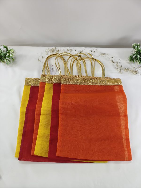 collection of bridal silk potli bags featuring rich hues of orange, red, and yellow, adorned with shimmering golden lace handle handmade potlis are designed as wedding favors, perfect for gifting at nikah ceremonies, bridal showers, or as bridesmaid gifts