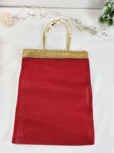 A set of bridal silk potli bags in rich orange, red, and yellow tones, embellished with golden lace handles, perfect for wedding favors and bridesmaid gifts. These handmade potlis are crafted with attention to detail
