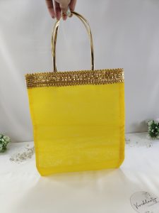 A beautiful assortment of bridal silk potli bags in shades of orange, red, and yellow, enhanced with golden lace handles, perfect for wedding favors and bridal shower gifts. These handmade potli bags are crafted with luxurious silk, making them ideal for gifting at nikah ceremonies or as a bride's wedding favor