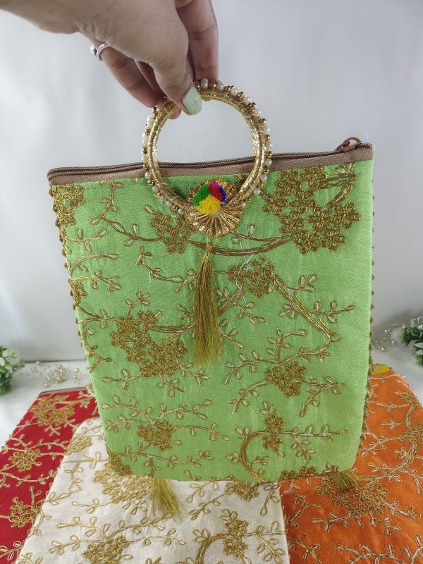 green embroidered wedding potli bag is intricately adorned with golden floral embroidery and features a stylish golden handle with a colorful tassel, making it a perfect wedding accessory for use as a bridal shower gift, wedding favor